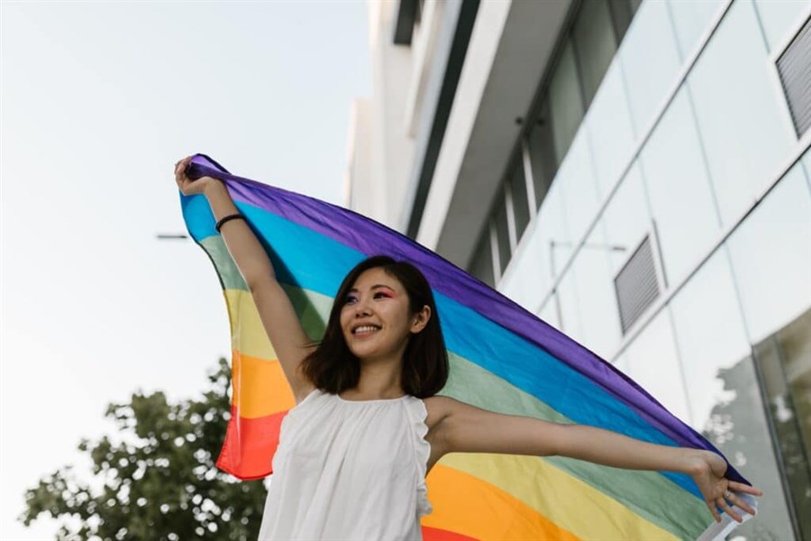 Meisje dat een regenboogvlag in de lucht houdt